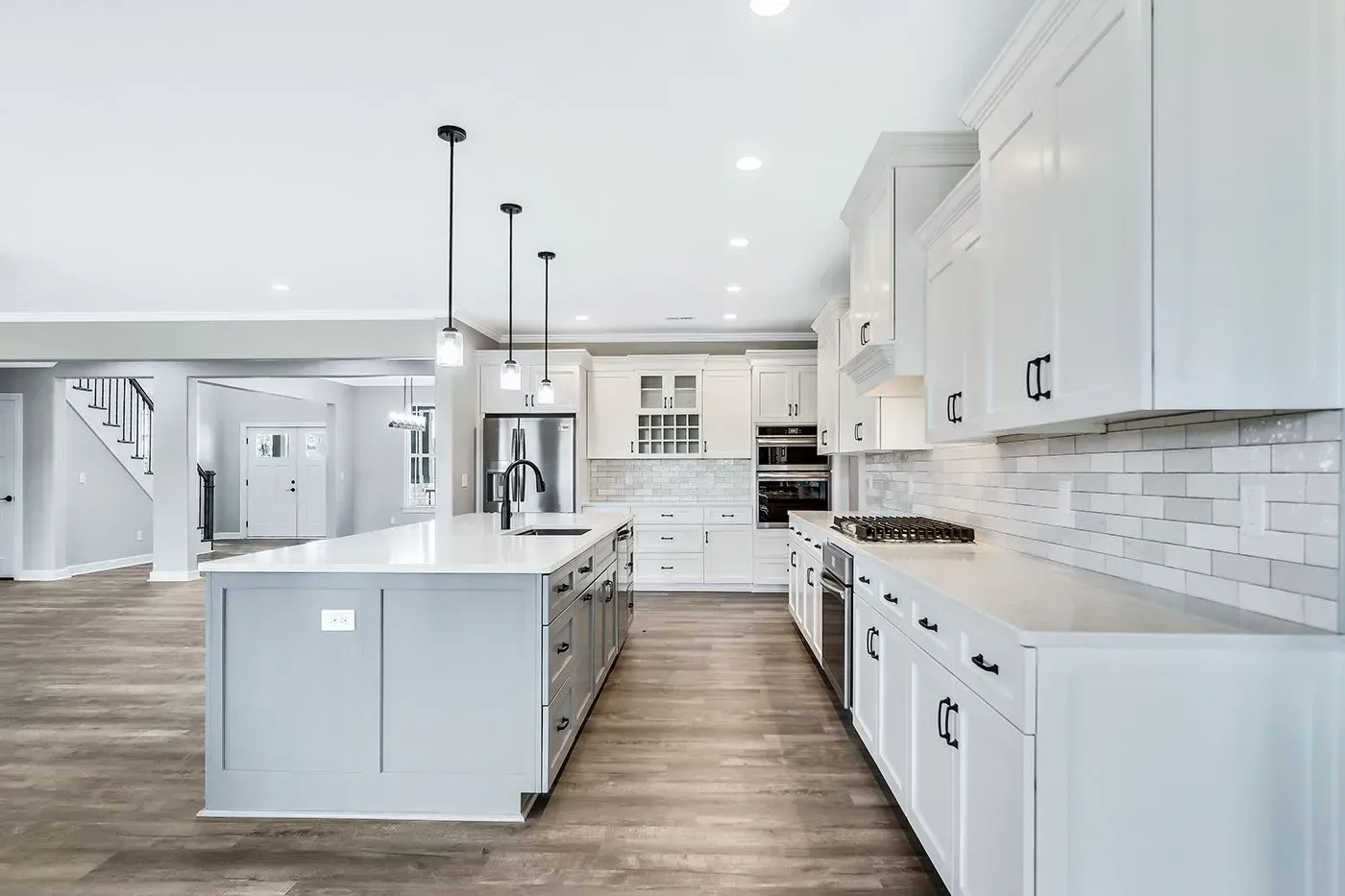 Bright white modern kitchen with island and cabinetry; stainless appliances, light wood floors.