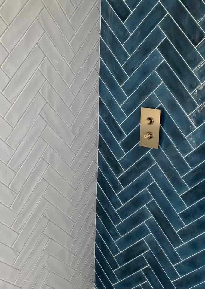 Blue herringbone tiled wall and grey herringbone tiled wall meeting at corner