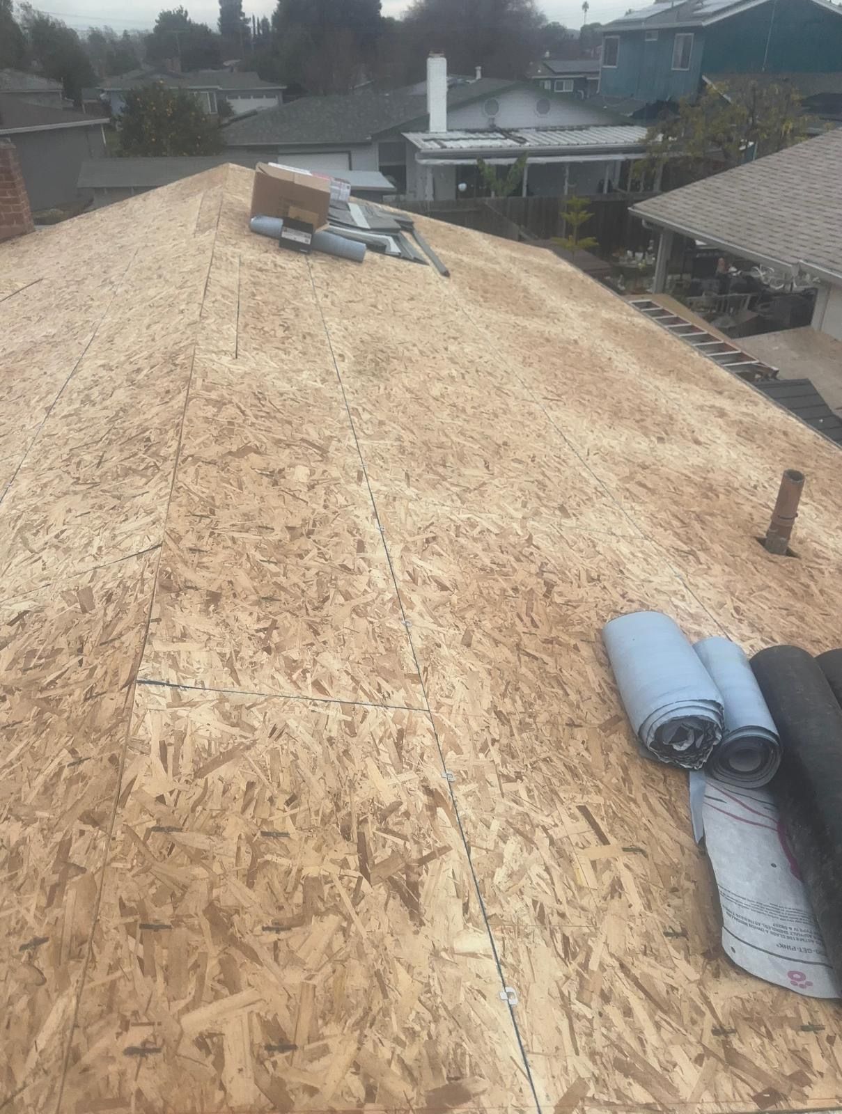 Roof under construction with plywood sheathing and rolled roofing materials on top