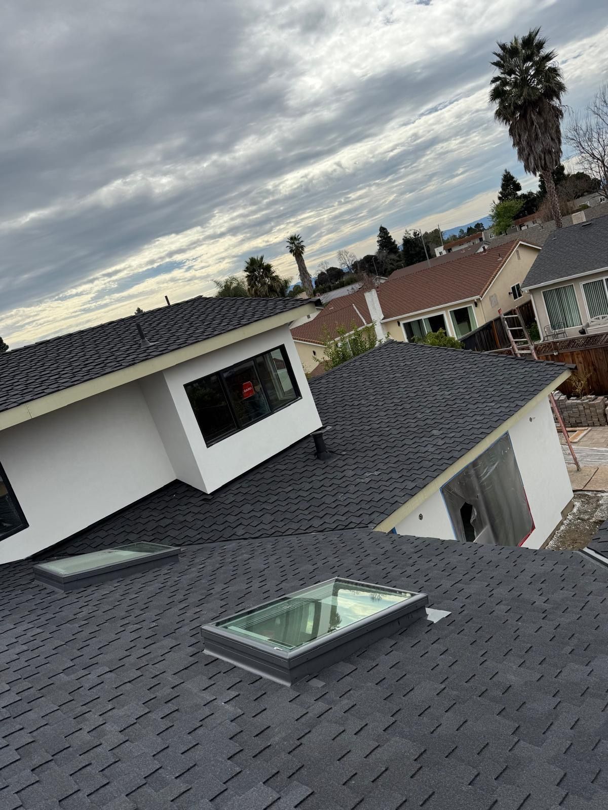Roofs of suburban homes under a cloudy sky, with a skylight in the foreground.