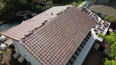 Aerial view of a house with a brown tiled roof and a section of lighter tiles near the edge.