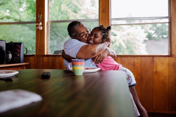 A woman is hugging a little girl while sitting at a table.