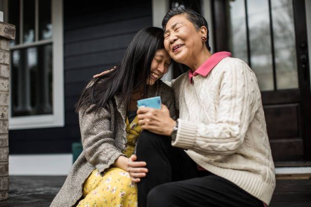 An older woman and a younger woman are sitting on the porch of a house.