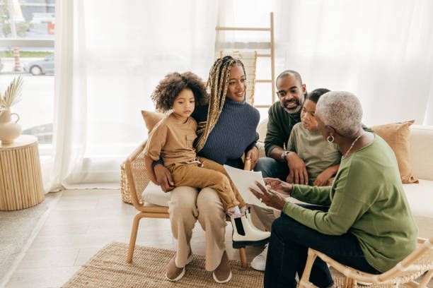 A family is sitting on a couch reading a book together.