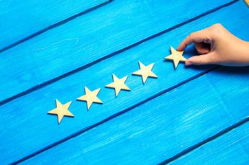 A person is holding a wooden star in their hand on a blue wooden table.