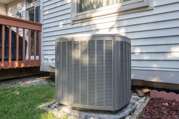 An air conditioner is sitting on the side of a house.