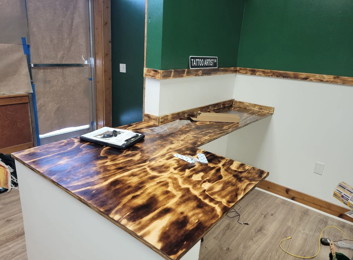 Burned wood countertop in an interior space, with white and green walls.