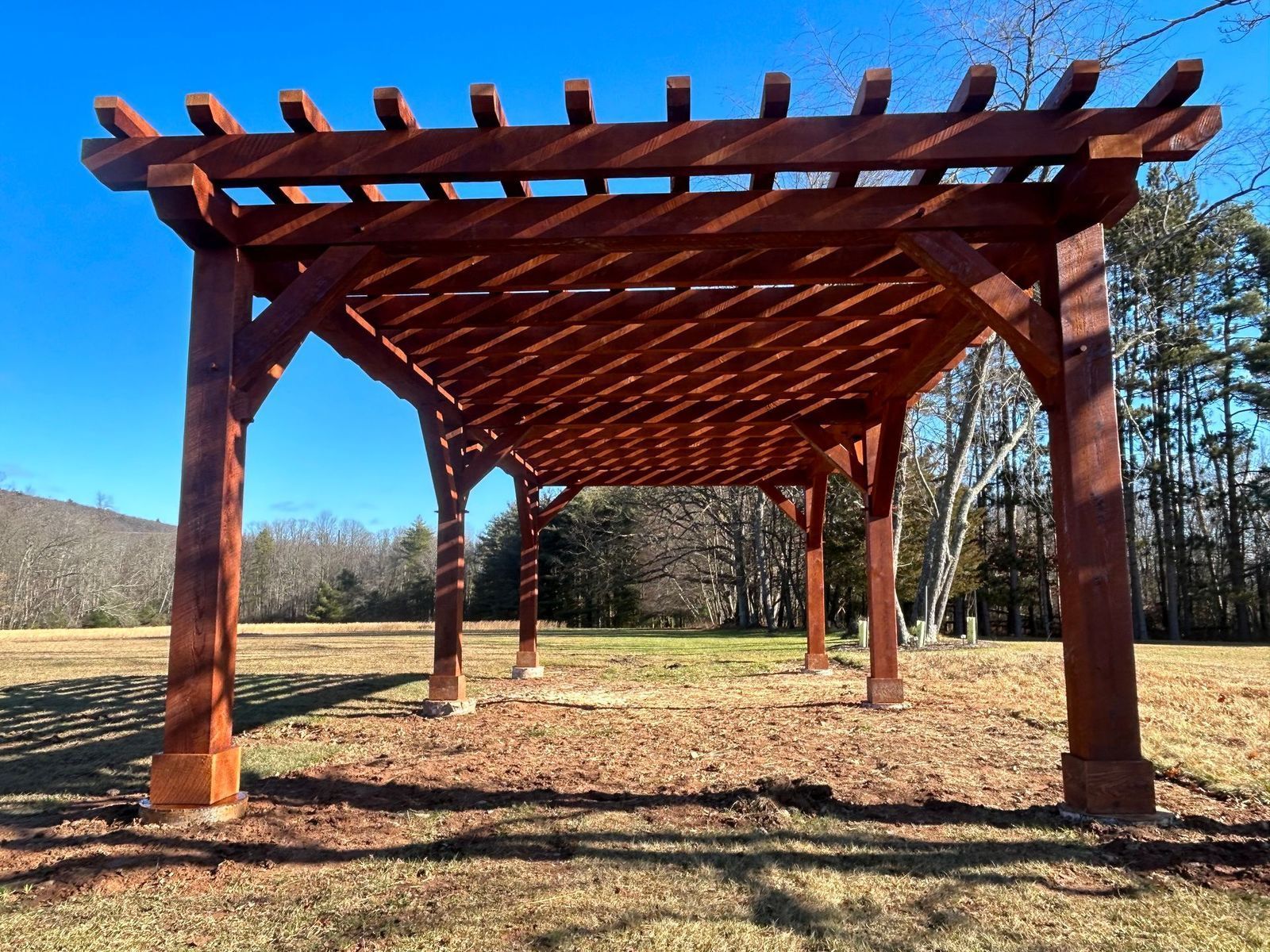 A large, wooden pergola by Central Timber Frame Supply with a lattice roof 