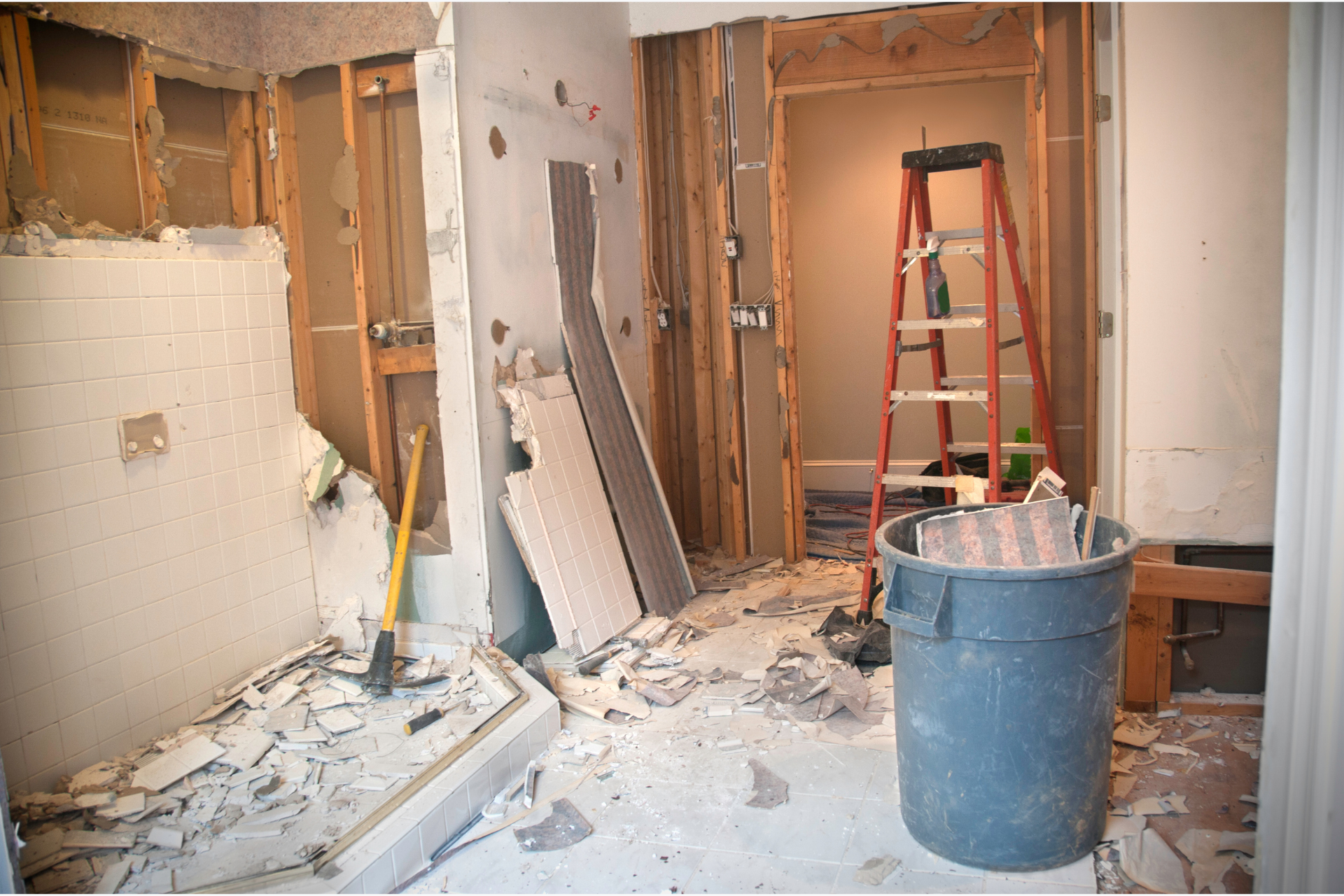 A room under construction with a ladder and a trash can