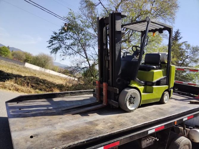 Una carretilla elevadora está sentada en la parte trasera de una grúa.