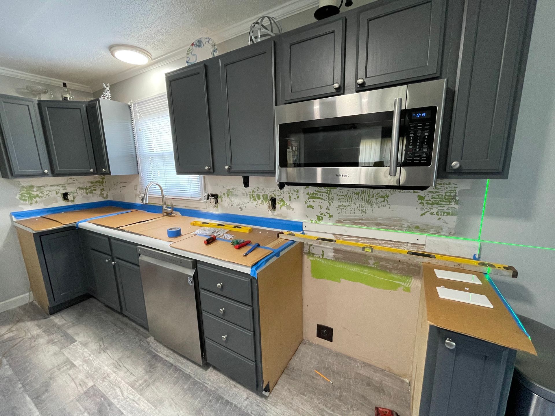 Kitchen remodel with gray cabinets, stainless steel appliances, and work in progress.
