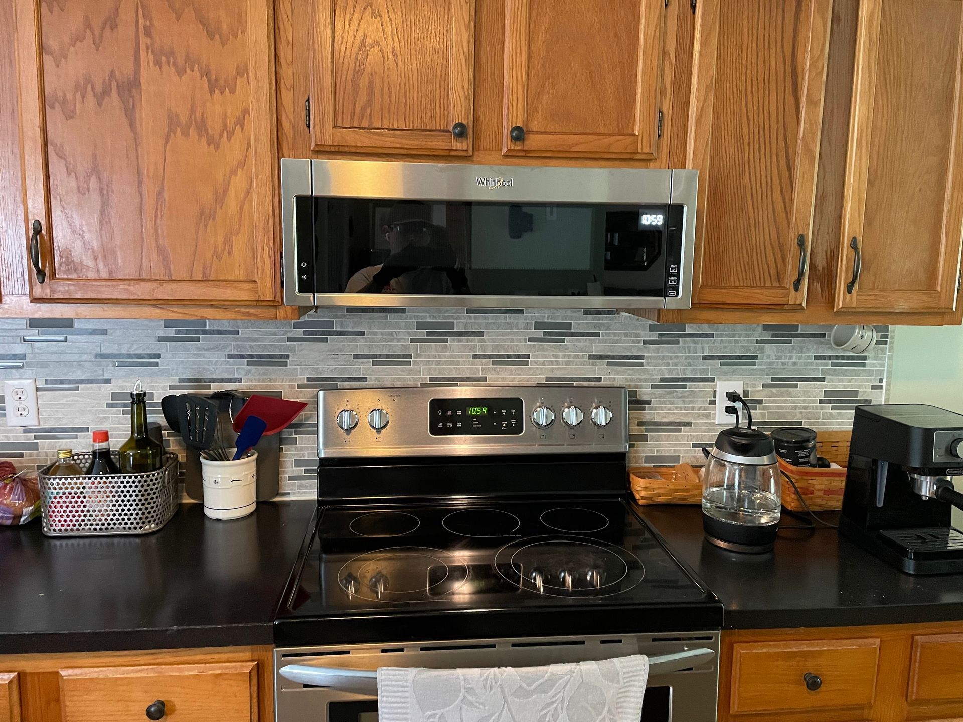 Kitchen with stove, microwave, wooden cabinets, and black countertop.