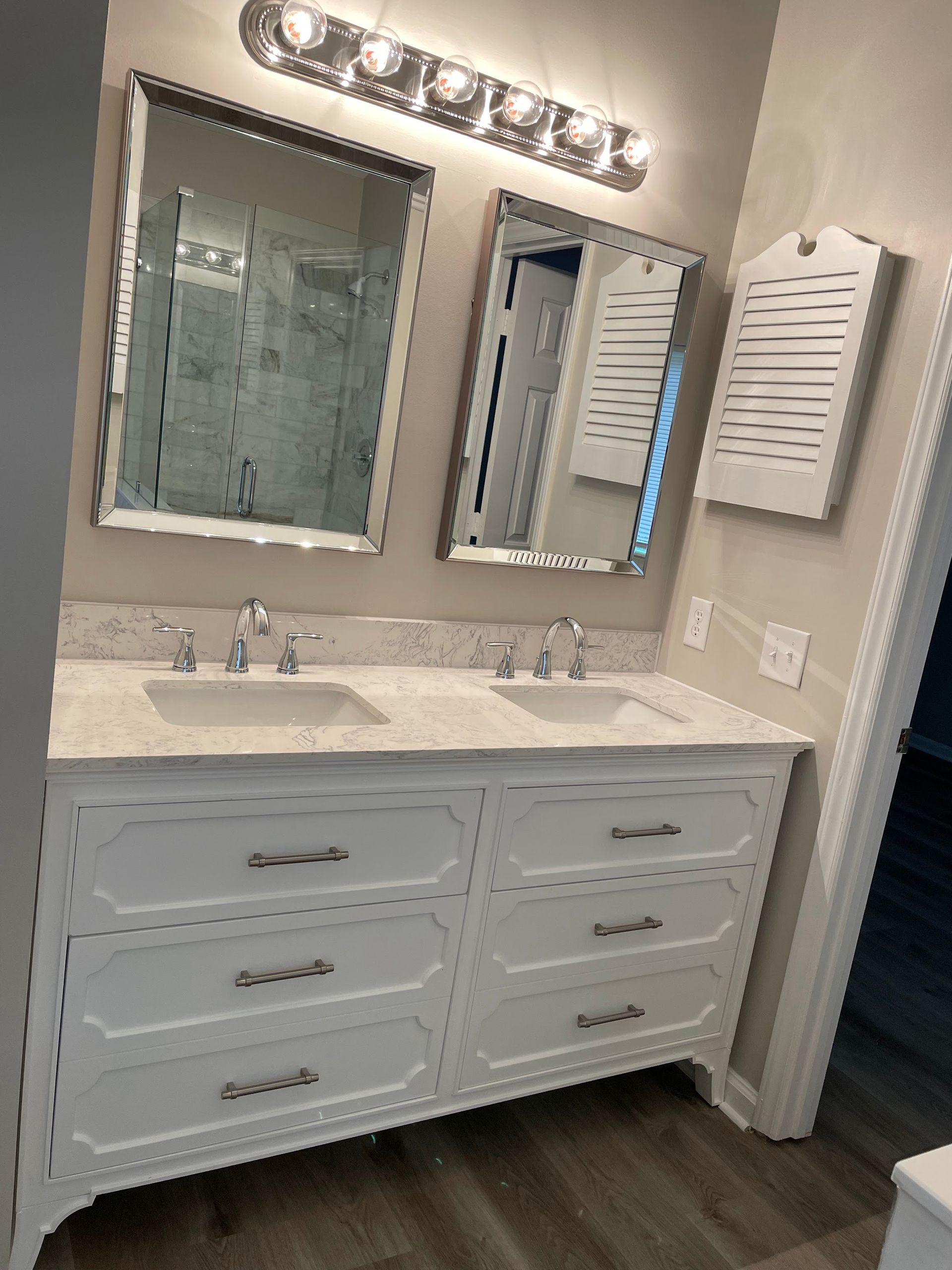 White double vanity with mirrors and a light fixture in a bathroom.