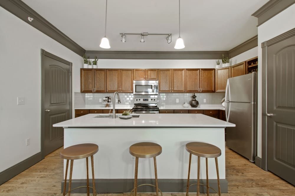 a kitchen with a large island, stools, and a refrigerator at Marquis on Evans in San Antonio, TX.