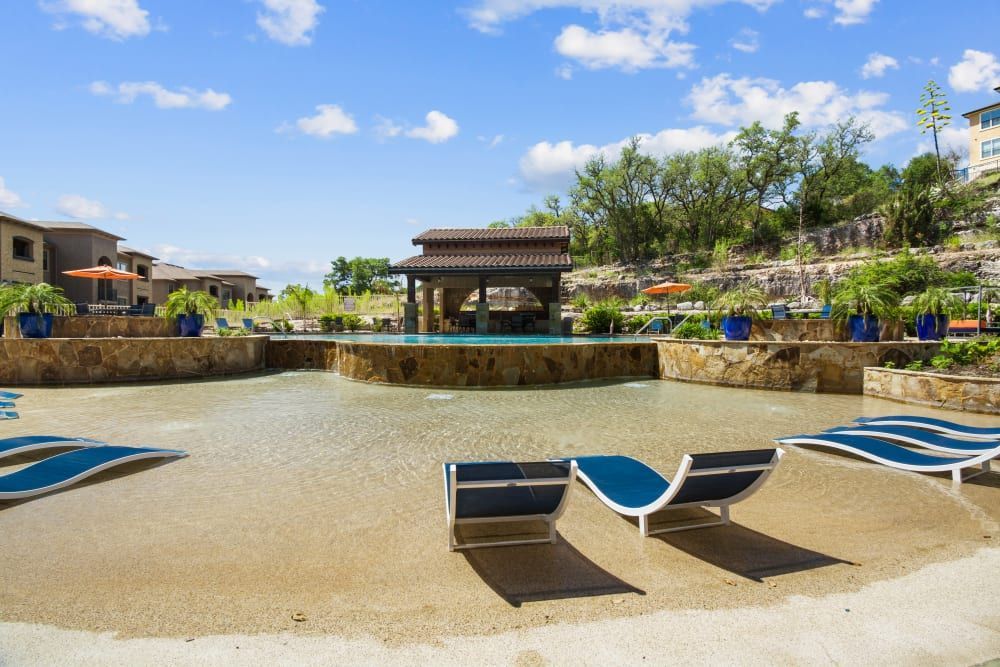 a swimming pool surrounded by lawn chairs on a sunny day at Marquis on Evans in San Antonio, TX.