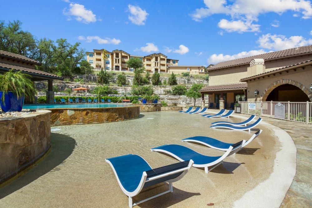 a row of blue lounge chairs are lined up in front of a swimming pool at Marquis on Evans in San Antonio, TX.