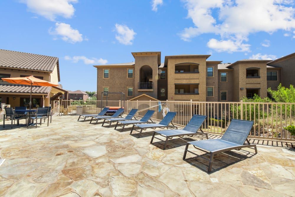 a row of lounge chairs are lined up on a patio in front of a building at Marquis on Evans in San Antonio, TX.