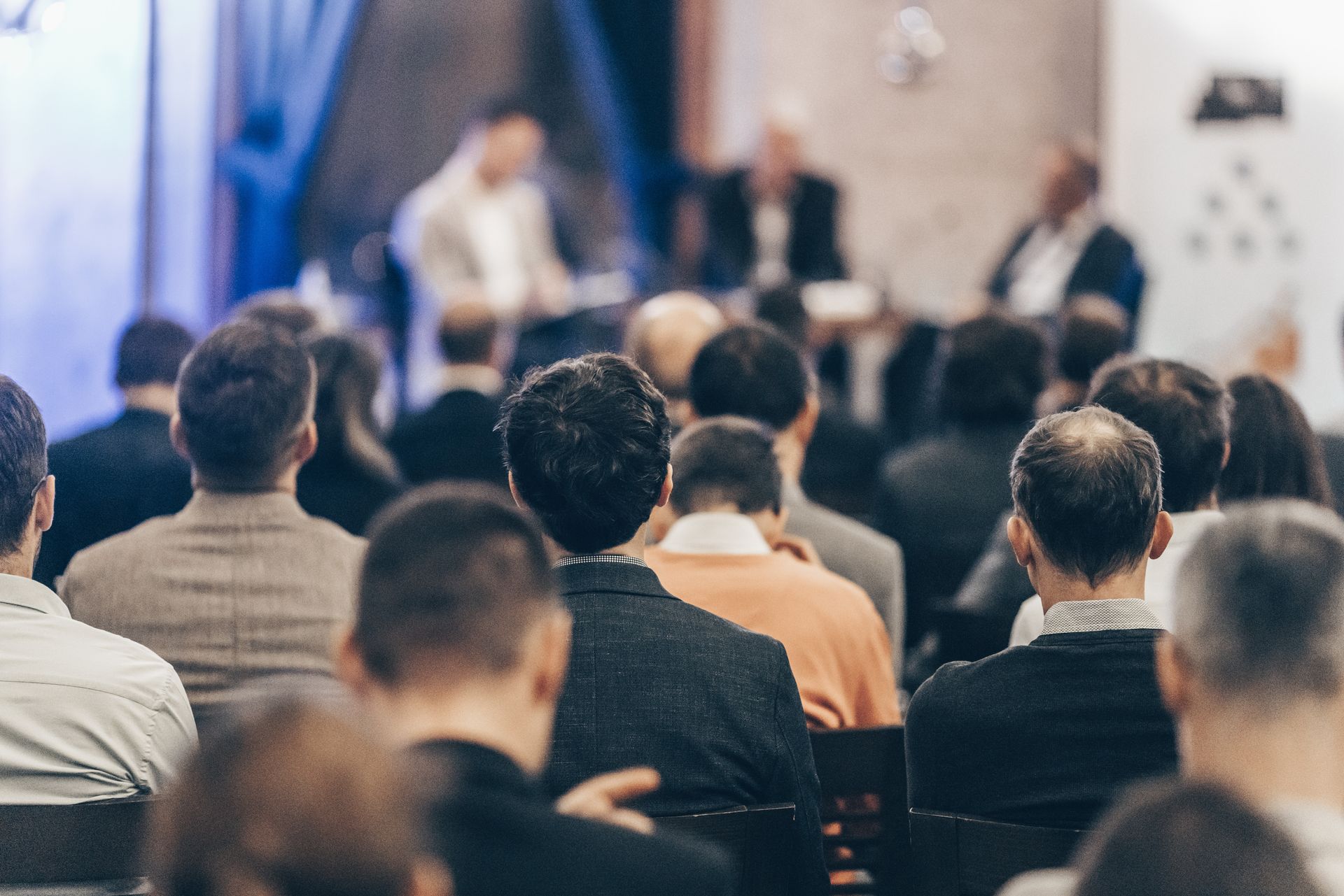 A large group of people are sitting in a room watching a presentation.