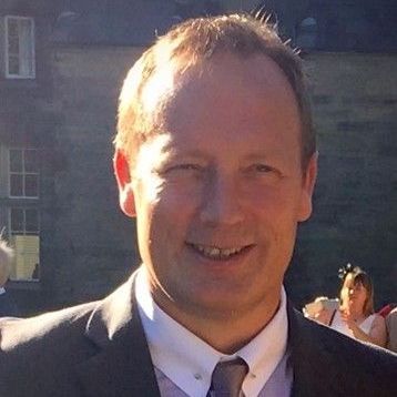 A man in a suit and tie is smiling for the camera