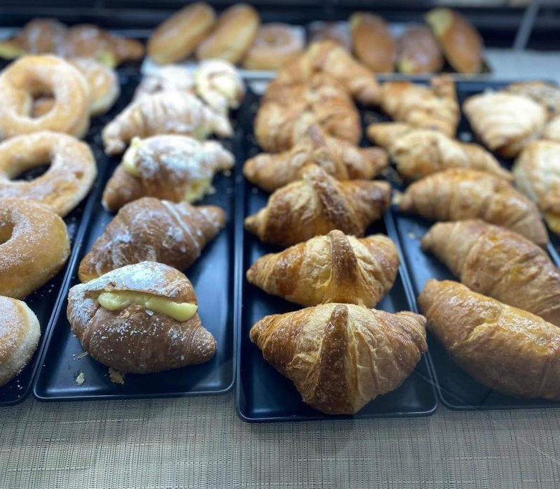Pasticcini esposti in una vetrina da forno, tra cui croissant, ciambelle e panini.