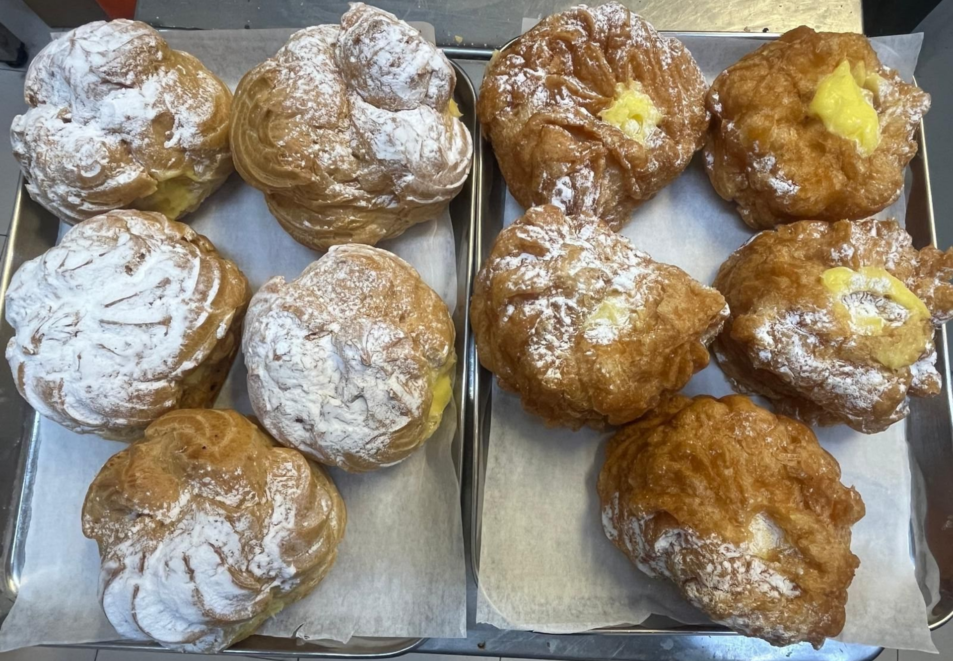 Pasticcini esposti in una vetrina da forno, tra cui croissant, ciambelle e panini.