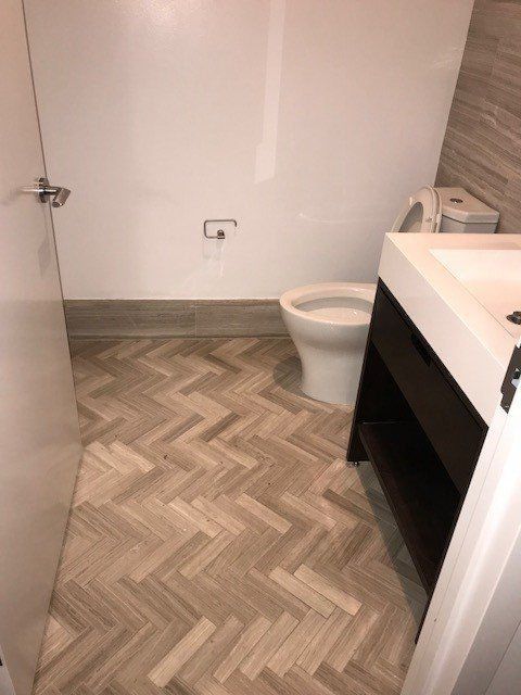 A bathroom with a herringbone floor and a toilet