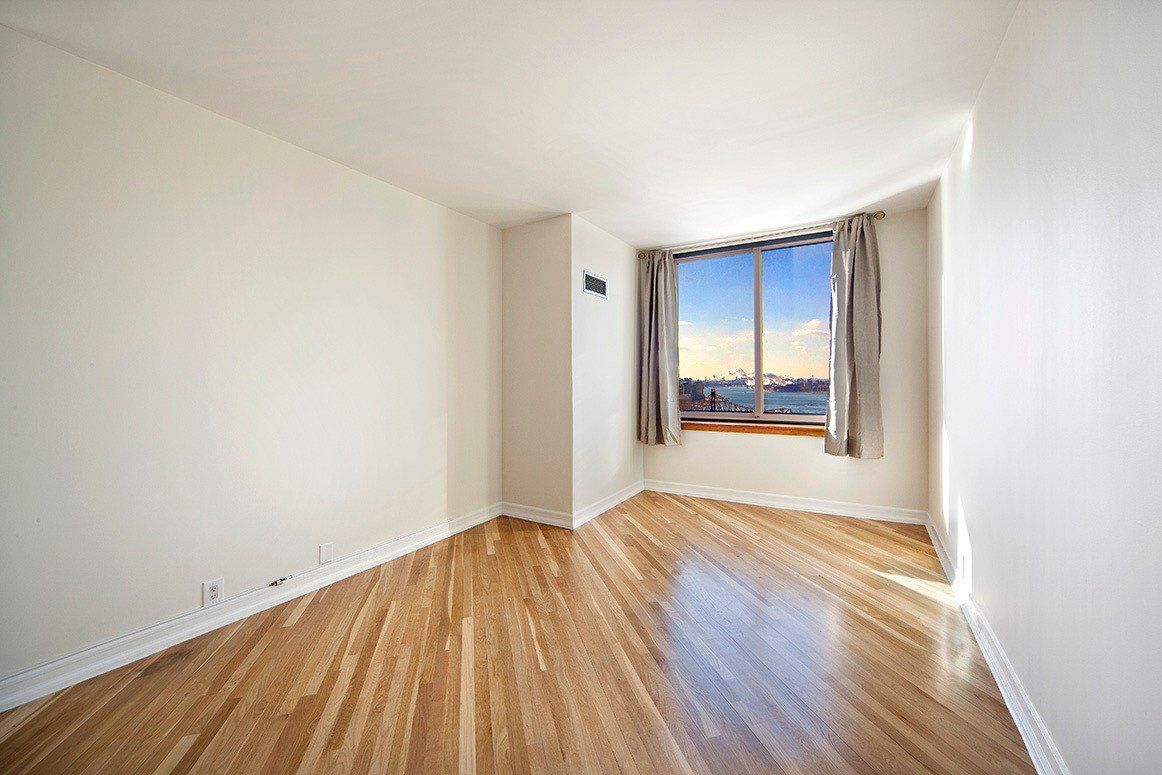 An empty room with hardwood floors and a large window.