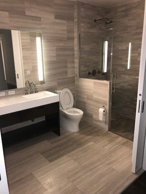 A bathroom with a toilet , sink and shower.