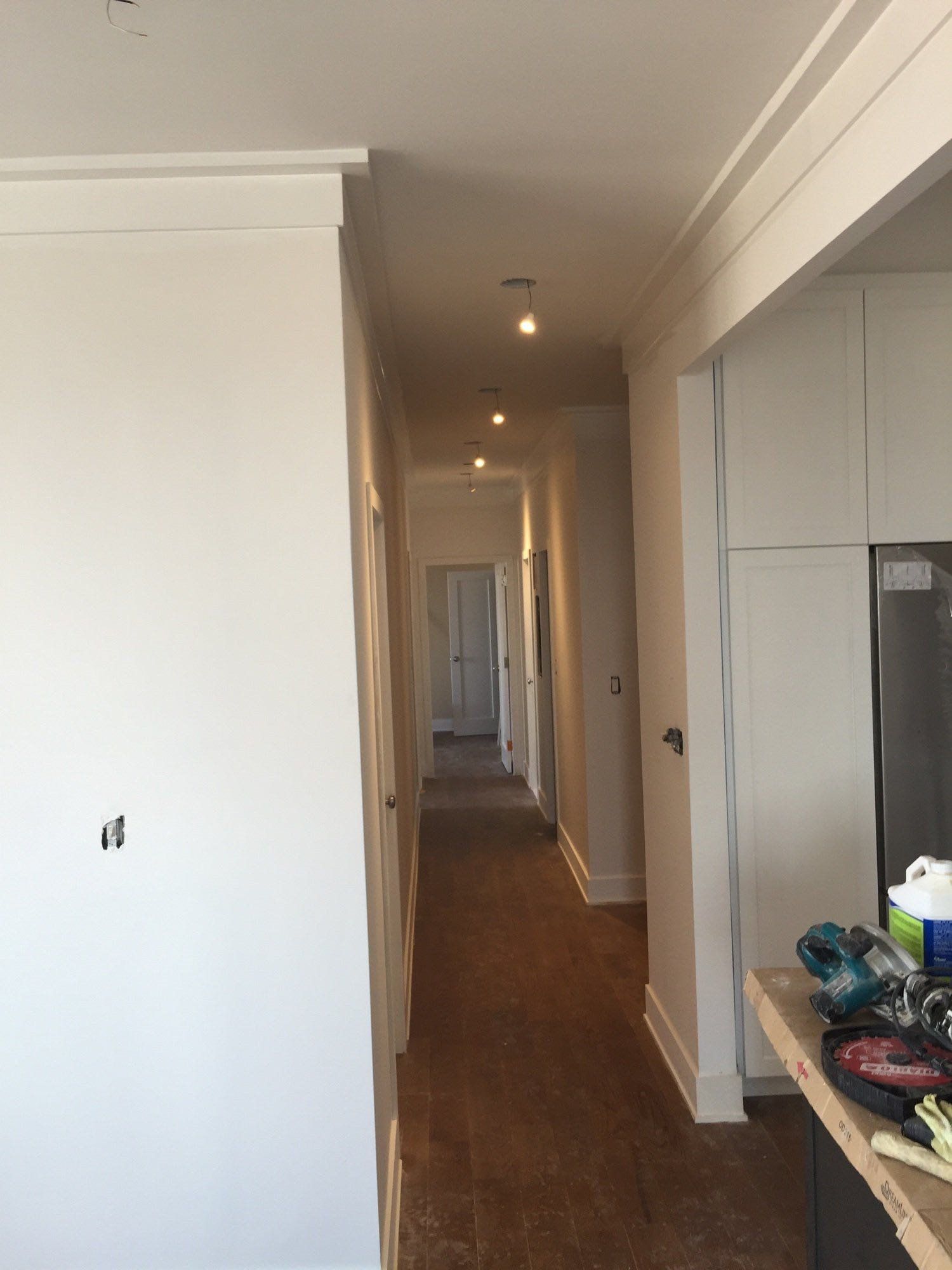 A hallway in a house with white walls and brown carpet
