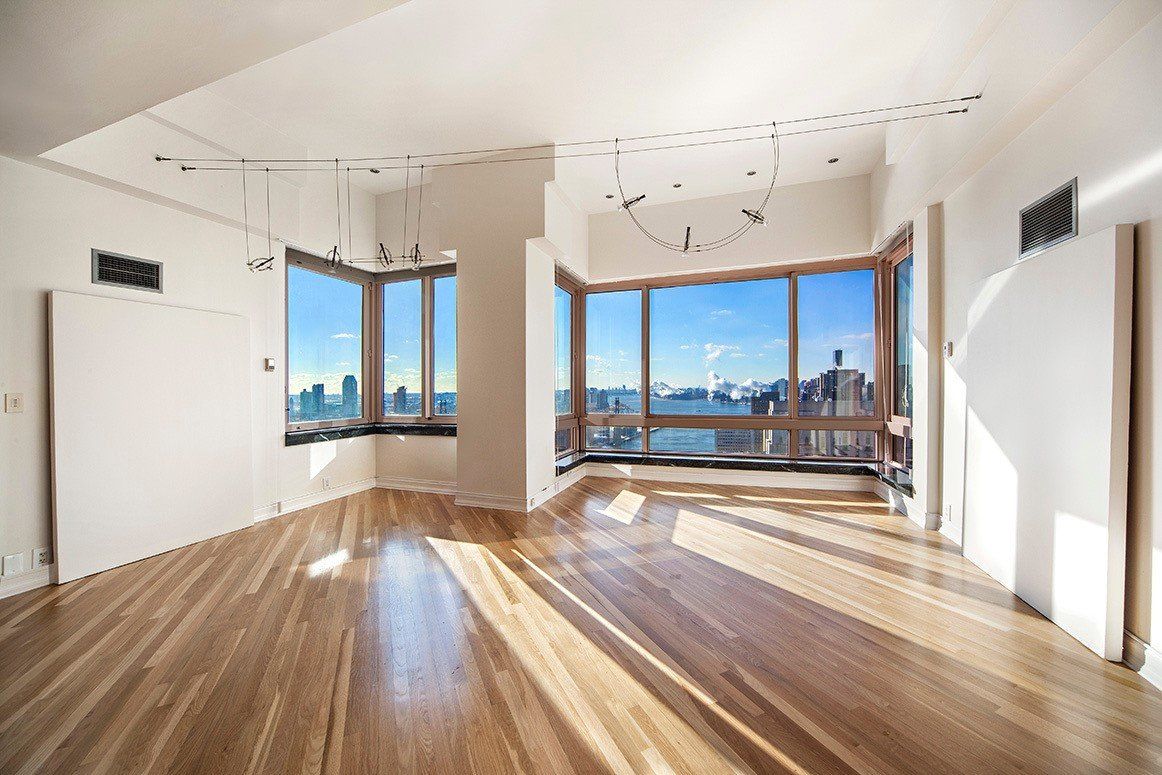 An empty living room with hardwood floors and lots of windows.