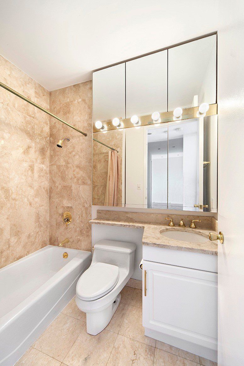 A bathroom with a toilet , sink , bathtub and mirror.