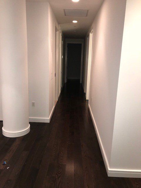 A long hallway with hardwood floors and white walls