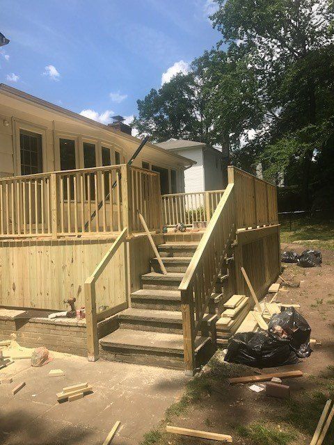 A wooden deck with stairs is being built in front of a house.