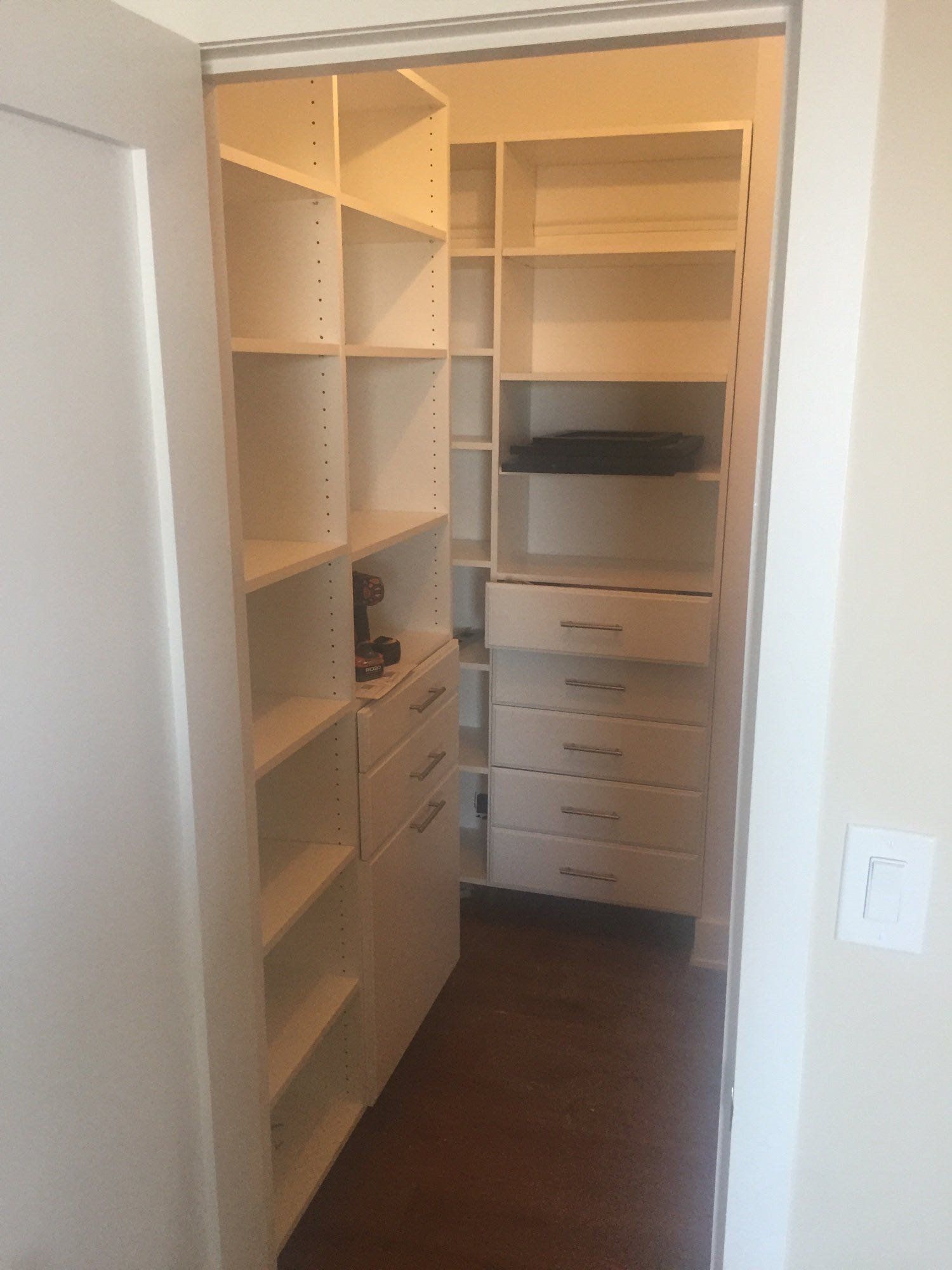 A walk in closet with lots of shelves and drawers