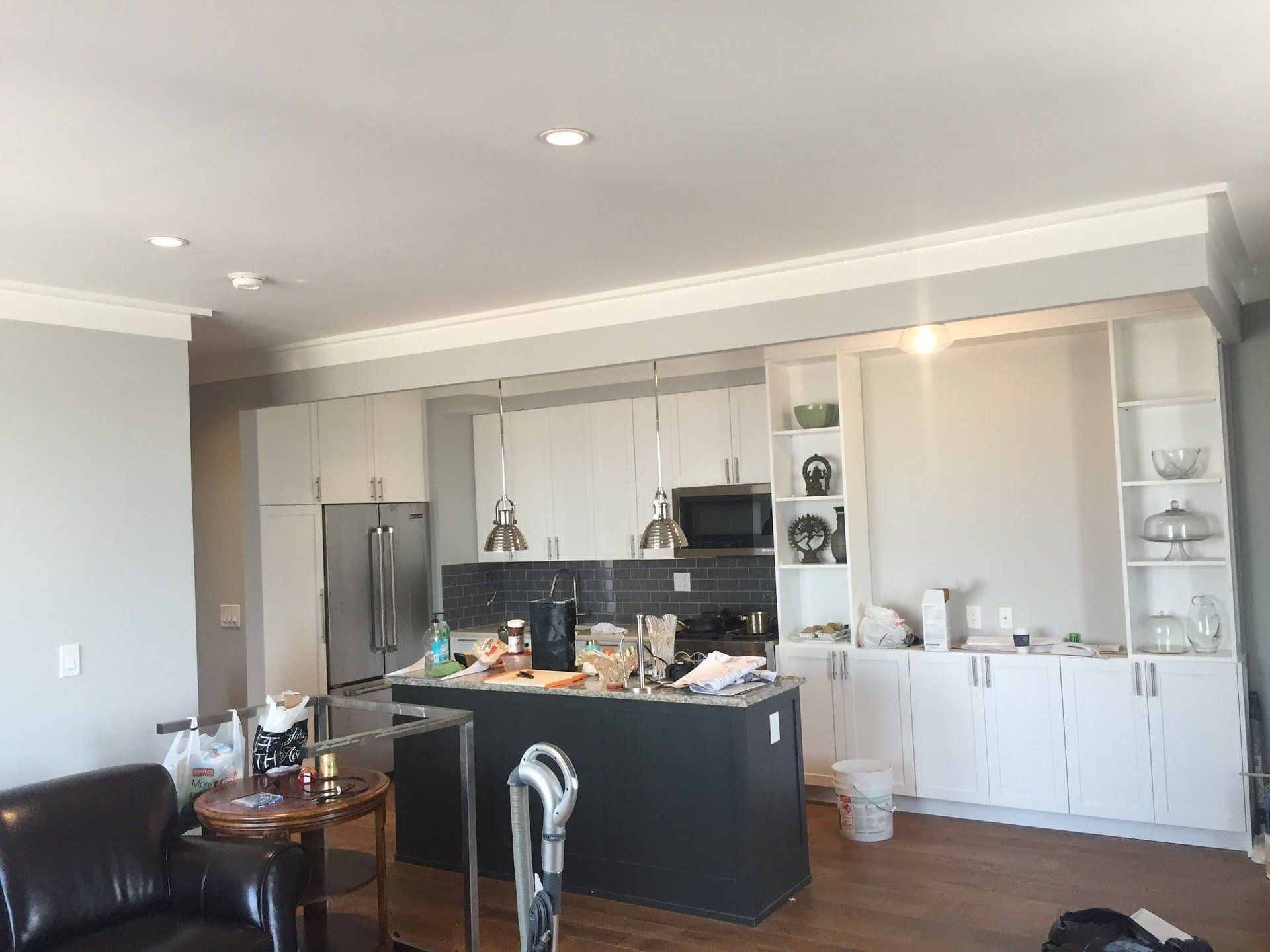 A kitchen with white cabinets and a black island in a living room.