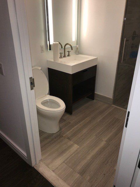 A bathroom with a toilet , sink and mirror.