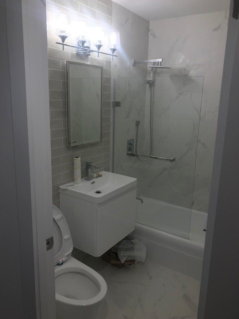 A bathroom with a toilet , sink , shower and mirror.