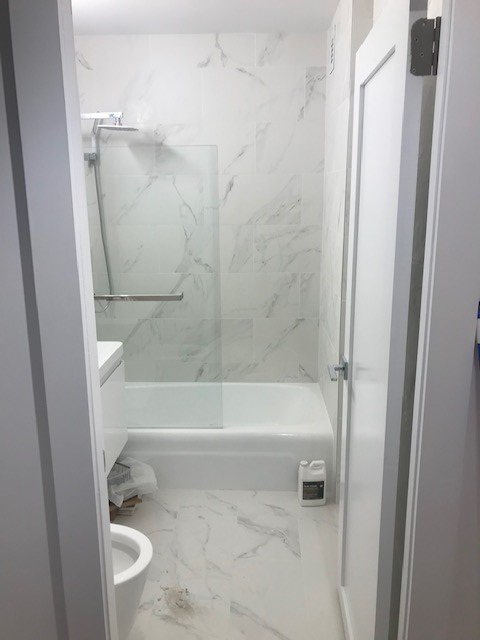 A bathroom with a bathtub , toilet , sink and shower.