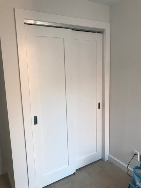 A white closet with sliding doors in a room