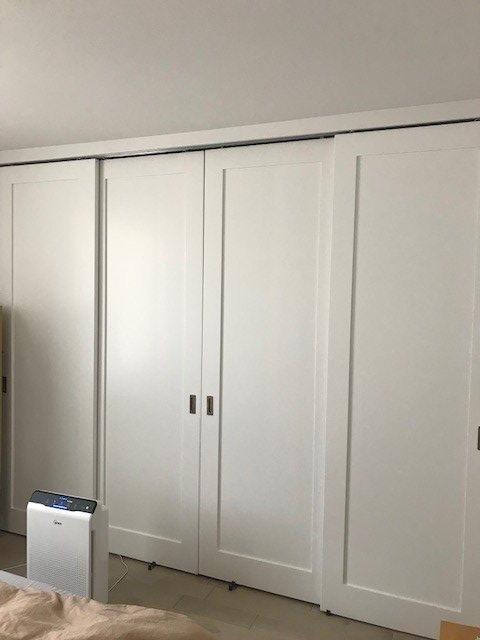 A bedroom with white sliding doors and a bed.