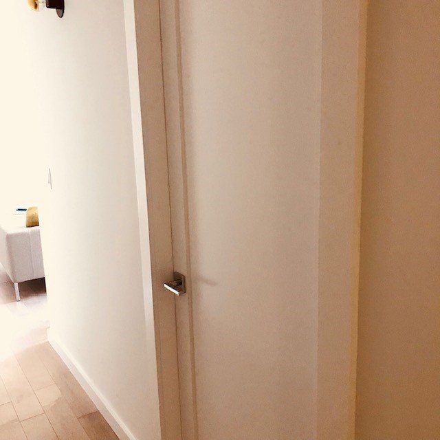 A hallway with a white door leading to a living room