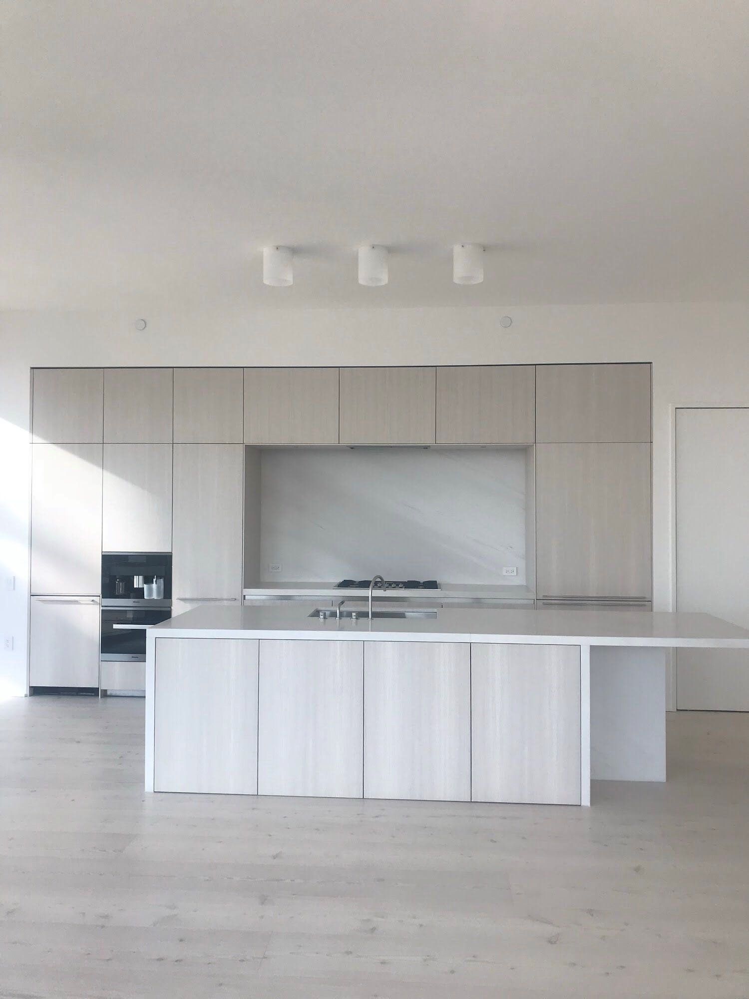 An empty kitchen with white cabinets and a large island