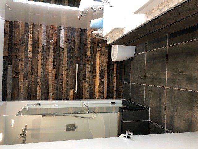 A bathroom with a wooden wall and a bathtub