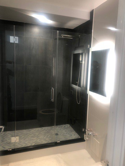 A bathroom with a glass shower door and a mirror.