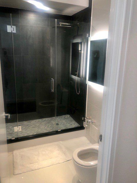 A bathroom with a toilet , shower , and mirror.