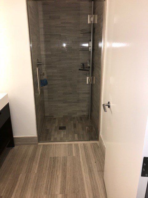 A bathroom with a walk in shower and a glass door.