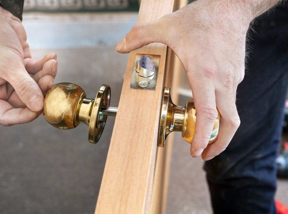 A man is installing a door knob on a wooden door.