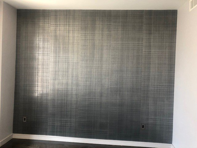 A room with a gray wall and a wooden floor.