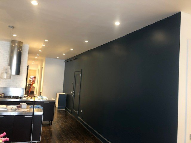 A kitchen with dark blue walls and wooden floors