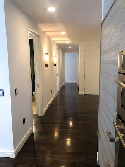 A long hallway with wooden floors and white walls